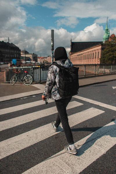Back view of man walking on crossroad on sunlit street in Copenhagen, Denmark 