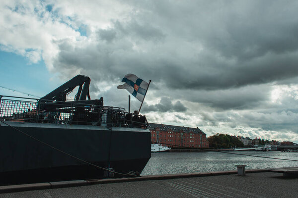 Docked ship on canal with buildings and cloudy sky at background, Copenhagen, Denmark 