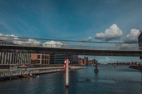 Bridge above canal with urban street and cloudy sky at background in Copenhagen, Denmark 