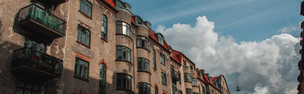 Panoramic orientation of facade of old building with sunlight and cloudy sky at background, Copenhagen, Denmark 