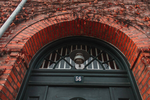 Low angle view of lantern near door and plant on brick facade of building in Copenhagen, Denmark 