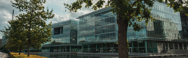 Panoramic shot of trees and glass facade of building near canal, Copenhagen, Denmark 