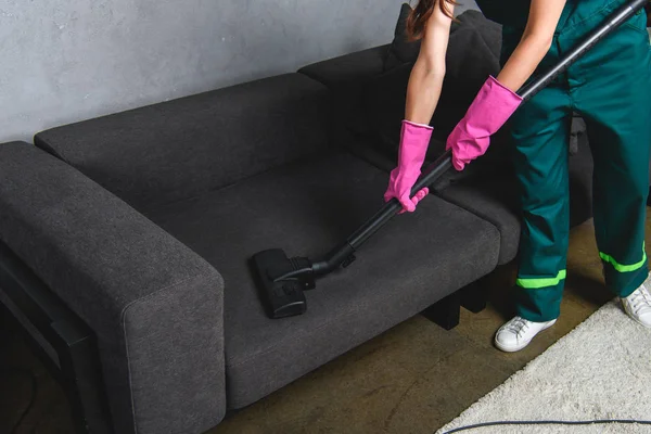 Vista de ángulo alto de la mujer en guantes de goma muebles de limpieza con aspiradora - foto de stock