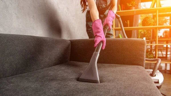 Обрізаний знімок жінки в гумових рукавичках чистий диван з пилососом — стокове фото