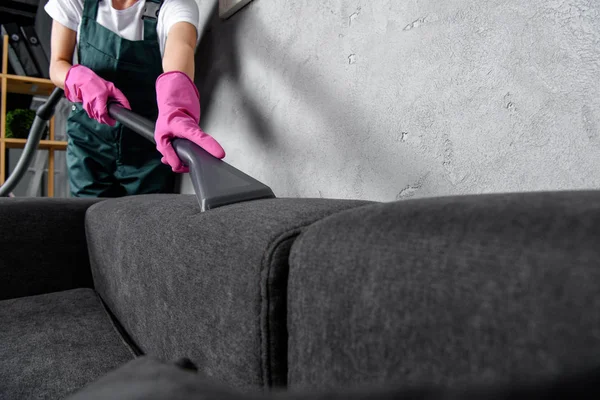 Plan recadré de la femme dans des gants en caoutchouc canapé de nettoyage avec aspirateur — Photo de stock