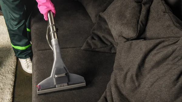 Partial view of person in rubber glove cleaning sofa with vacuum cleaner — Stock Photo