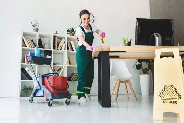 Blick auf lächelnden jungen Hausmeister, der modernes Büro putzt — Stockfoto