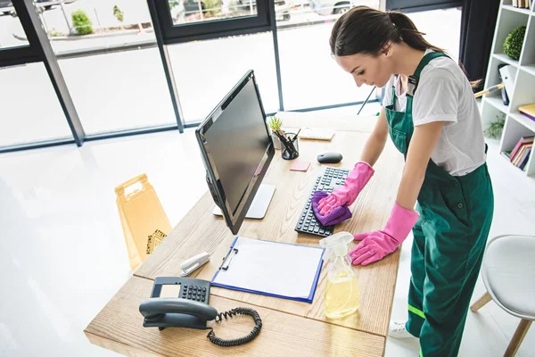 Высокий угол обзора молодой женщины в резиновых перчатках уборка офисного стола — стоковое фото