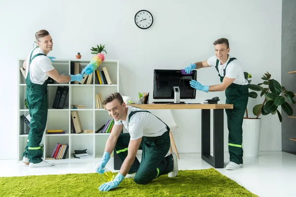 Collage de jeunes travailleurs heureux nettoyage de bureau et sourire à la caméra — Photo de stock