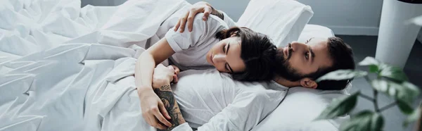 Молодая пара в пижаме, обнимающая, лежа дома в постели с копировальным местом — стоковое фото