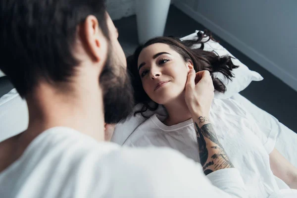 Бородатый татуированный мужчина обнимает красивую женщину в постели — стоковое фото