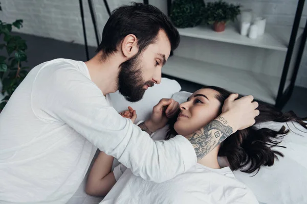 Bonito barbudo homem abraçando bela mulher em casa na cama — Fotografia de Stock