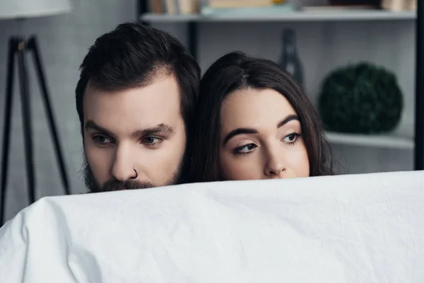 Selective focus of beautiful romantic young couple holding blanket at home — Stock Photo