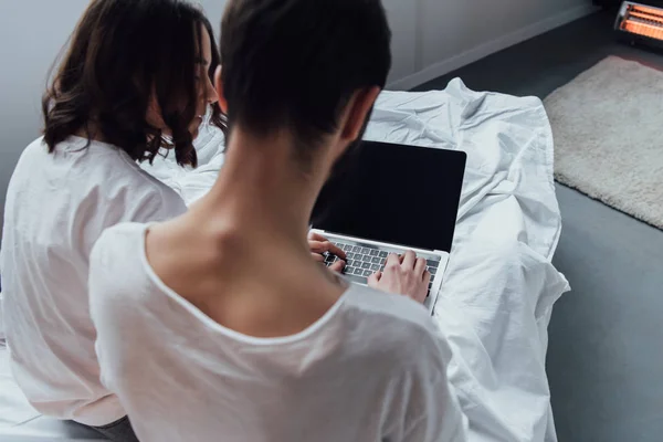 Vista posteriore della coppia sdraiata a letto e utilizzando laptop con schermo bianco — Foto stock