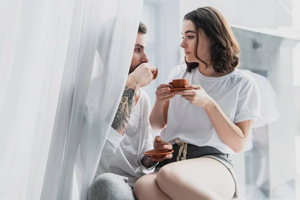 Beautiful young couple drinking coffee at home in morning — Stock Photo