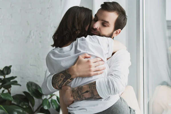 Belo jovem casal apaixonadamente abraçando em casa — Fotografia de Stock