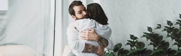 Bonito tatuado homem apaixonadamente abraçando mulher em casa com cópia espaço — Fotografia de Stock