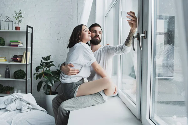 Belo jovem casal tomando selfie no smartphone em casa — Fotografia de Stock