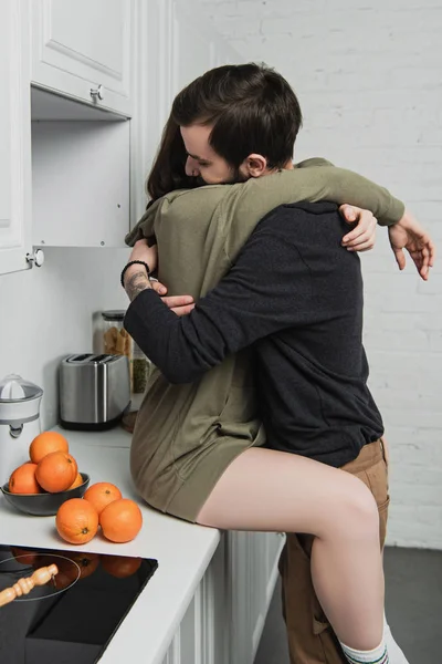 Belo jovem casal abraçando em kithcen durante o café da manhã — Fotografia de Stock