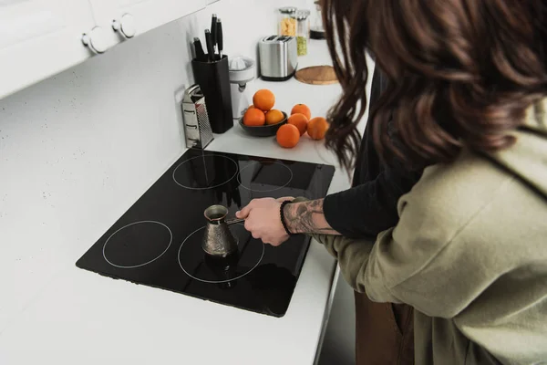 Vista recortada de la pareja preparando café en cezve durante el desayuno por la mañana - foto de stock