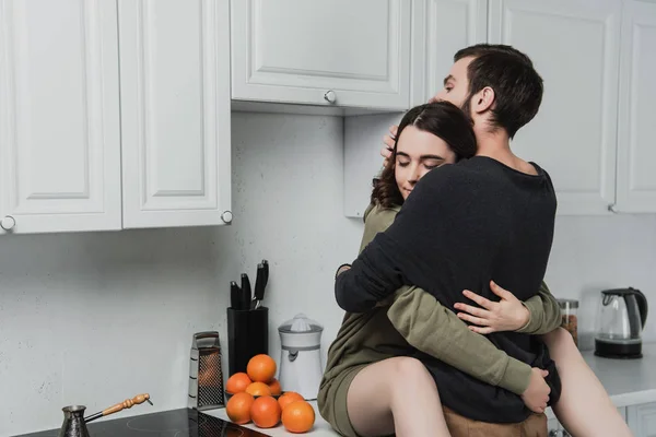 Belo amor jovem casal abraçando em kithchen durante o café da manhã — Fotografia de Stock