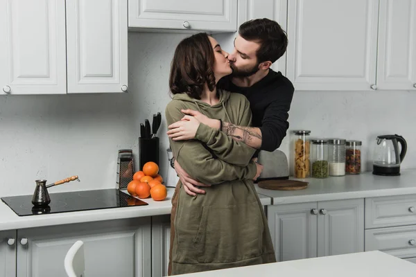Красива молода пара обіймає і цілує в кітчен під час сніданку — стокове фото