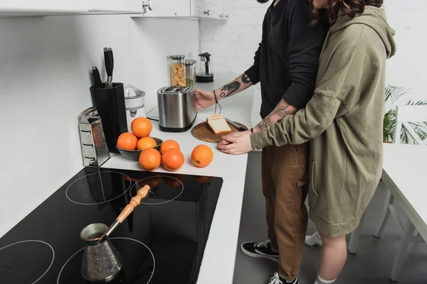 Vista parcial de pareja joven preparando brindis juntos durante el desayuno en la cocina - foto de stock