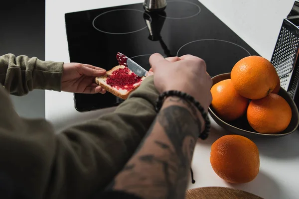Teilansicht eines Paares, das beim Frühstück in der Küche Toasts mit Marmelade zubereitet — Stockfoto