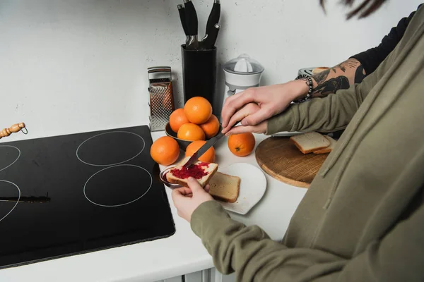 Abgeschnittene Ansicht eines Paares, das beim Frühstück in der Küche Toasts mit Marmelade zubereitet — Stockfoto