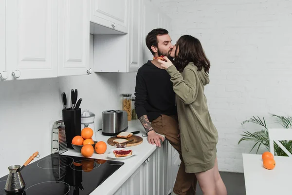 Beautiful young romantic couple kissing during breakfast in kitchen — Stock Photo