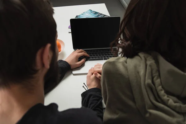 Back view of couple sitting and using laptop with blank screen at home — Stock Photo