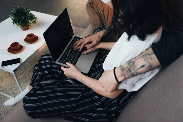 Abgeschnittene Ansicht eines Paares, das sitzt und sich umarmt, während es Laptop mit leerem Bildschirm zu Hause benutzt — Stockfoto