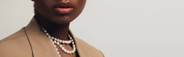 Cropped view of african american woman in beige jacket and necklace isolated on grey — Stock Photo