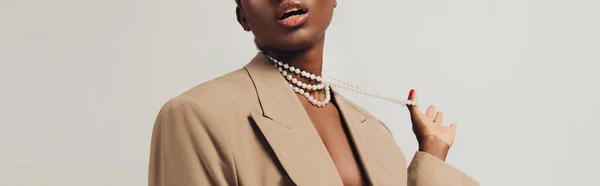 Vista cortada de mulher americana africana sedutora em jaqueta bege e colar isolado em cinza — Fotografia de Stock