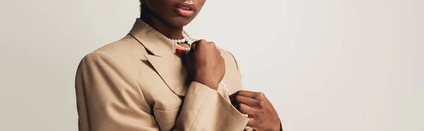 Vista recortada de la mujer afroamericana de moda en chaqueta beige aislada en gris - foto de stock