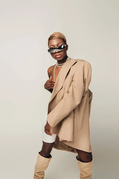 Chica afroamericana desnuda posando en chaqueta beige aislada en gris - foto de stock