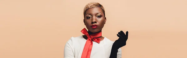 Alla moda attraente ragazza africana americana in posa in sciarpa rossa e guanti neri isolati su beige — Foto stock