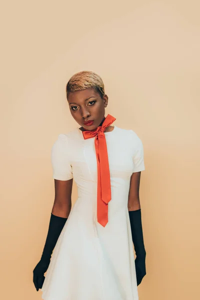 Belle fille afro-américaine posant en écharpe rouge et gants noirs isolés sur beige — Photo de stock