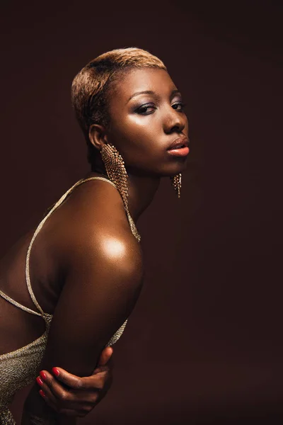 Dispara de moda con mujer afroamericana con el pelo corto aislado en marrón - foto de stock