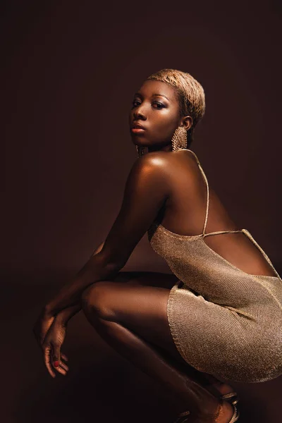Молодая гламурная африканская американка с короткими волосами, изолированная от коричневых — стоковое фото