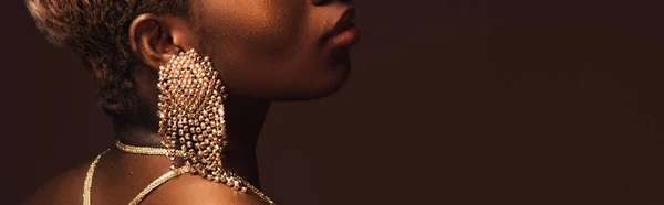 Vue recadrée de femme afro-américaine dans des boucles d'oreilles à la mode isolé sur brun — Photo de stock