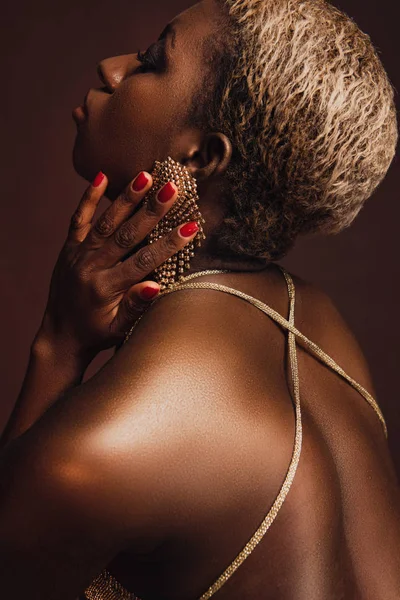 Vue latérale de la femme afro-américaine attrayante avec les cheveux courts isolés sur brun — Photo de stock