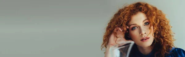 Panoramic shot of beautiful redhead young woman looking at camera on grey with copy space — Stock Photo