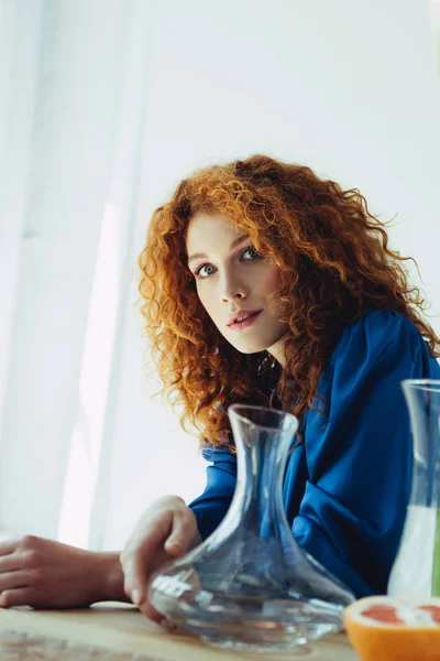 Beautiful stylish redhead woman posing near glass vases — Stock Photo
