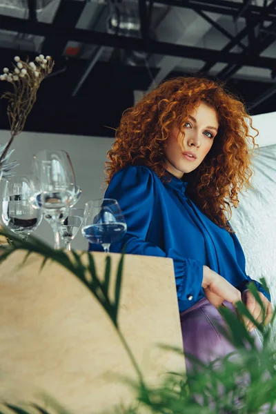 Beautiful redhead girl looking at camera near glasses with water — Stock Photo