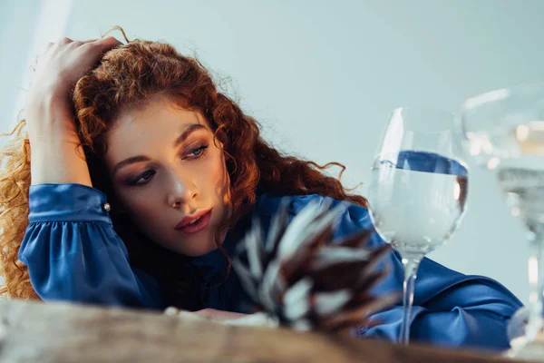 Belle femme rousse élégante posant près de lunettes avec de l'eau isolée sur gris — Photo de stock