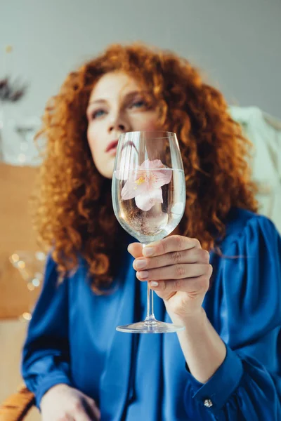 Schöne stilvolle rothaarige Frau hält Glas mit Blume — Stockfoto