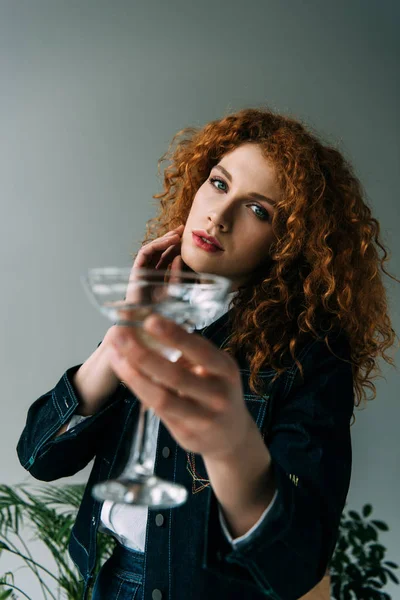 Belle femme rousse élégante posant avec du verre sur gris — Photo de stock