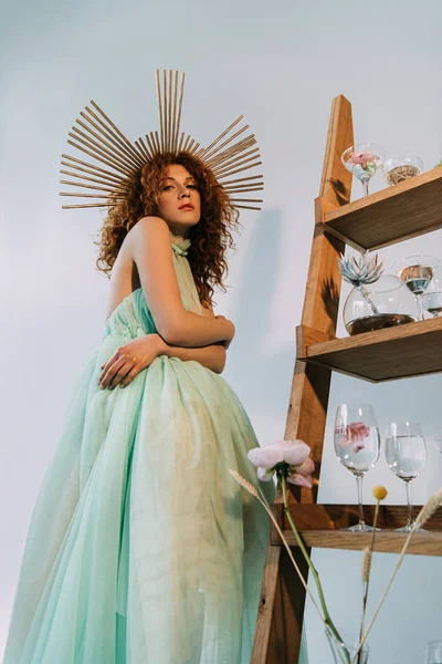 Menina ruiva elegante com acessório na cabeça posando perto de escada com flores e óculos — Fotografia de Stock