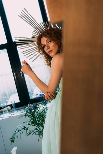 Beautiful stylish redhead girl with accessory on head in dress looking at camera — Stock Photo